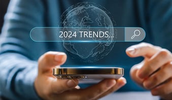 2024 trends in a search bar with a man holding a cell phone