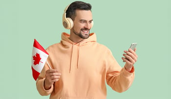 man holding and looking at a cell phone while holding a canadia flag